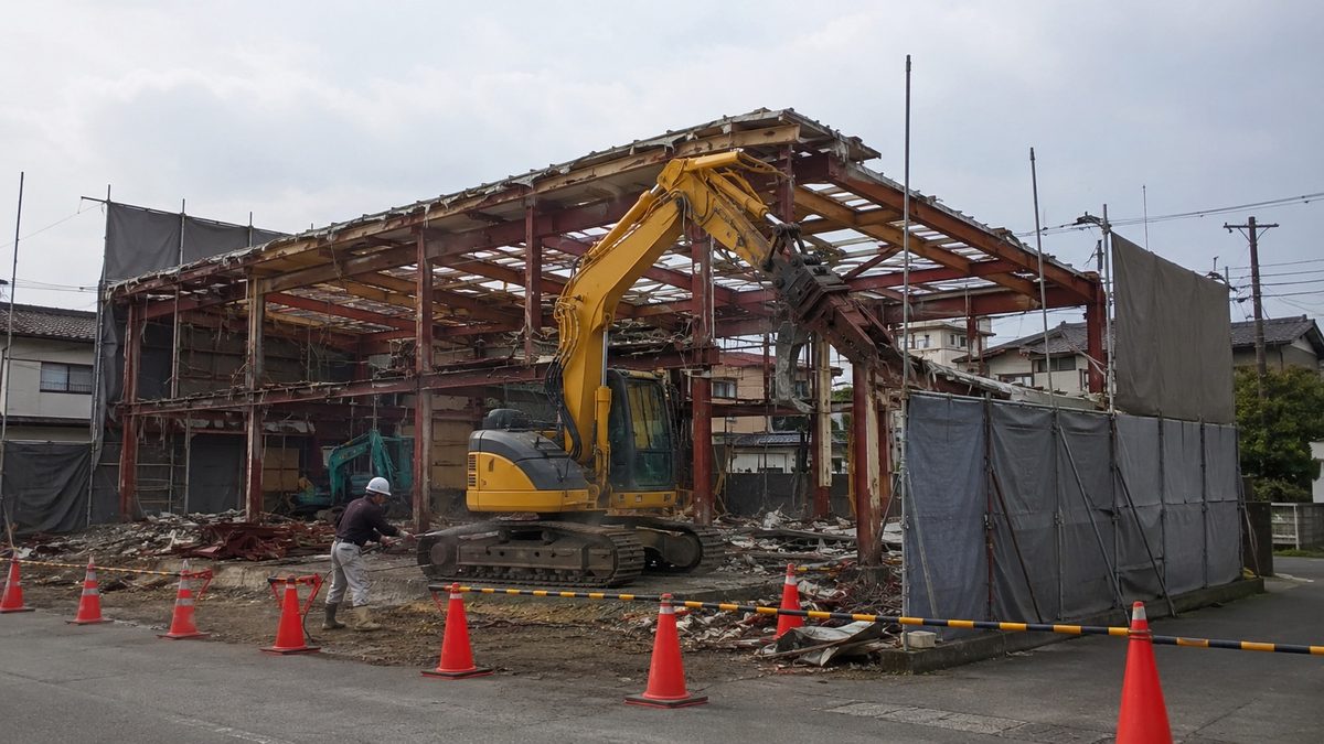 低層の鉄骨建物を重機で解体する現場（AI・構成見本）